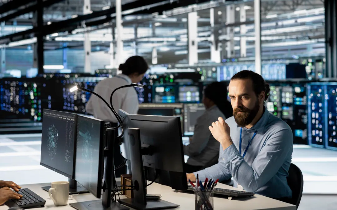 A technician reviewing system monitoring on a workstation in a server room